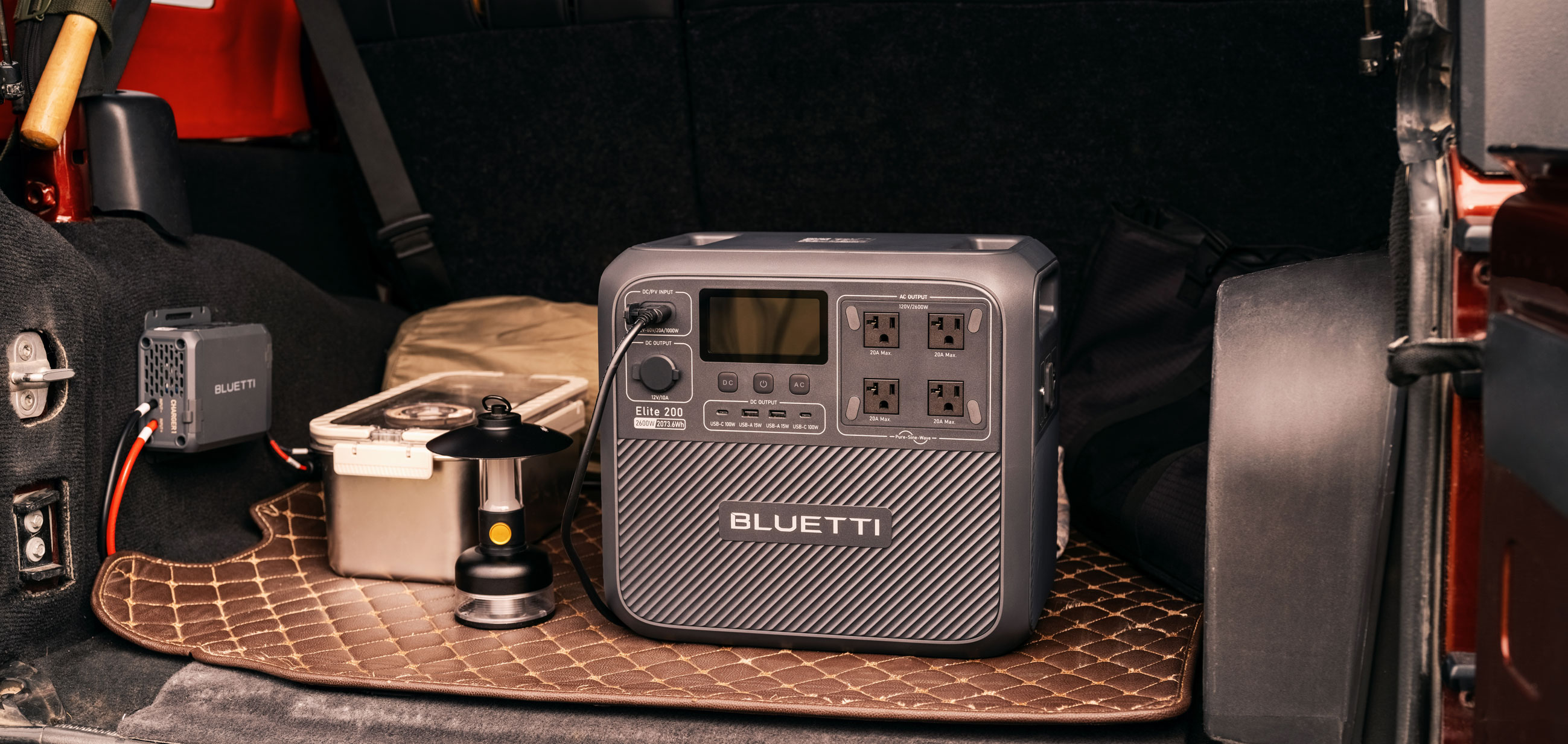 A photo showing the Bluetti Elite 200 V2 portable battery in the back of a Jeep, hooked up to the Charger 1 alternator charger